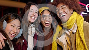 Young diverse friends laughing to the camera standing outdoors on winter