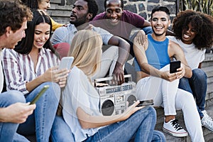 Young diverse people dancing and listening music with boombox stereo outdoor in the city - Main focus on transgender man face