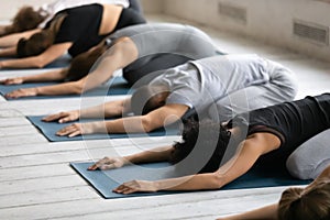 Young diverse people relaxing on floor mat in child pose. photo