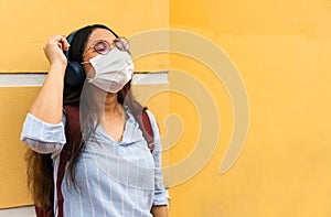Young diverse woman listening to music standing next to yellow wall with eyes closed
