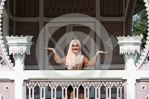 Young diverse woman raising hands in the air wearing hijab and smiling outdoors