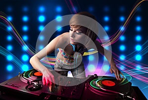 Young Dj girl mixing records with colorful lights