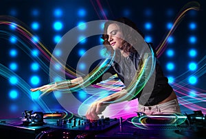 Young Dj girl mixing records with colorful lights