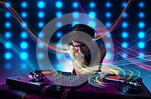 Young Dj mixing records with colorful lights