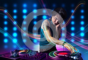 Young Dj mixing records with colorful lights