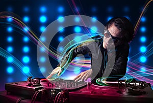 Young Dj mixing records with colorful lights