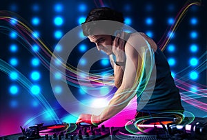 Young Dj mixing records with colorful lights