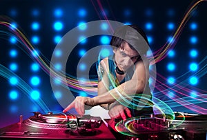 Young Dj mixing records with colorful lights