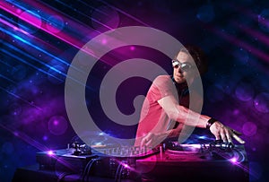 Young DJ playing on turntables with color light effects