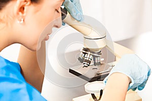 Young doctor assistant working with microscope