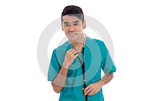 A young doctor in the blue dress with stethoscope smiles and looks into a camera