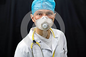 A young doctor in blue gloves and a stethoscope around his neck on a black background. Portrait of a doctor with medical