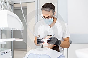 Young doctor drilling teeth to female patient