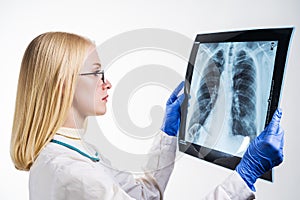 Young doctor examines chest x-ray on white background
