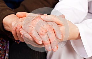 Young doctor holds the elderly woman hands