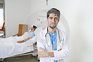 Young doctor at hospital bedroom with sick patient lying in bed