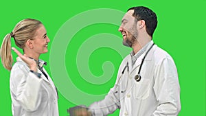 Young doctor joking on his collegue not give five on a Green Screen, Chroma Key.