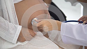 Young doctor listening heartbeat of baby