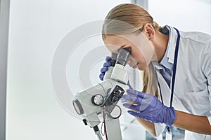 Young doctor looking through colposcope at laboratory