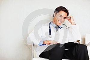 Young doctor looking at medical reports at hospital. Smiling young doctor looking at medical reports at hospital.