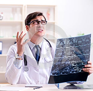 Young doctor looking at x-ray images in clinic