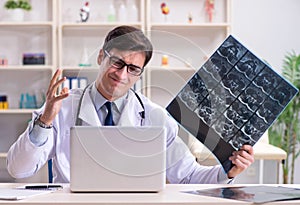 Young doctor looking at x-ray images in clinic