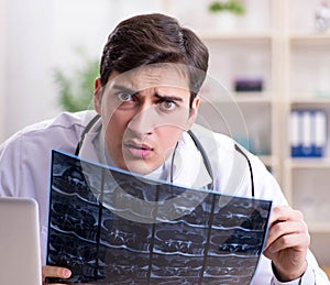 Young doctor looking at x-ray images in clinic