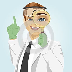 Young doctor with magnifying glass and safety goggles pointing up