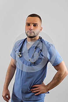 Young doctor man in blue uniform with stethoscope posign at studio. Medical worker