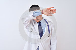 Young doctor man wearing stethoscope over isolated background covering eyes with arm, looking serious and sad