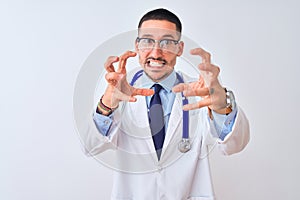 Young doctor man wearing stethoscope over isolated background Shouting frustrated with rage, hands trying to strangle, yelling mad