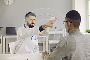 Young doctor measuring patient`s body temperature with a non-contact thermometer