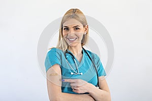 Young doctor, medical worker pointing at her arm with a bandage after receiving the covid-19 vaccine. Young nurse showing her