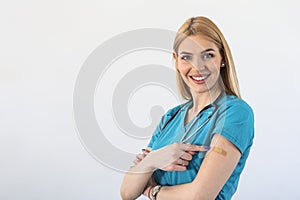 Young doctor, medical worker pointing at her arm with a bandage after receiving the covid-19 vaccine. Young nurse showing her