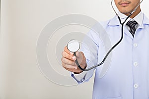 Young doctor, physician holding his stethoscope in hand at clinic or hospital