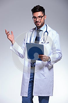 Young doctor presenting with clipboard in hand