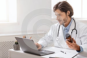 Young doctor reading instruction for pills on laptop