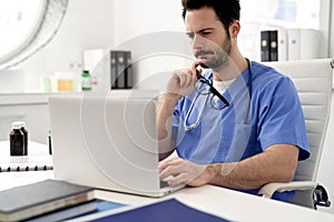 Young doctor reflects while working on the laptop