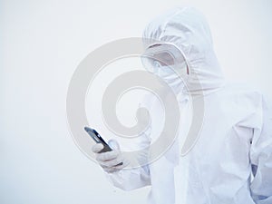 Young doctor or scientist in PPE suite uniform while playing his phone for chats with family or freind. coronavirus or COVID-19