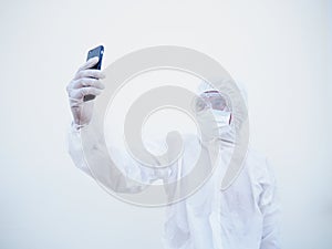 Young doctor or scientist in PPE suite uniform while using his phone for selfie and video chats with family or freind. coronavirus