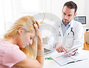 Young doctor showing results on tablet to patient