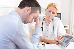 Young doctor showing results on tablet to patient