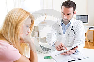 Young doctor showing results on tablet to patient