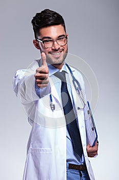 Young doctor shows thumb up and smiles