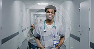 Young doctor stands in middle of hospital corridor