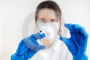 A young doctor with a syringe and a vaccine in his hands. Doctor indoors makes vaccination. A woman in a medical office.