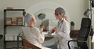 Young doctor talk to older female patient during visit