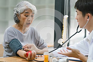 A young doctor using digital tonometer check blood pressure for senior woman. A doctor is holding a senior woman's