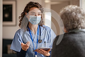 Young doctor visits senior woman with surgical mask