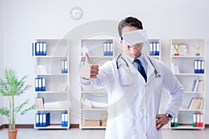 Young doctor with vr virtual reality headset working in the offi